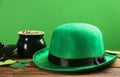 Leprechaun hat, decorative clover leaves and pot of gold on wooden table against green background. St Patrick`s Day celebration Royalty Free Stock Photo