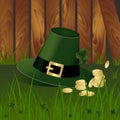 Leprechaun hat with fhree-leafed clover and golden coins on background with green grass and wooden garden fence. St. Patrick s day