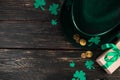 Leprechaun hat, gold coins, clover shamrock and green ribbon gift on dark wooden background. Good luck symbols for