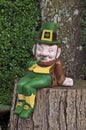 Leprechaun smiling and sitting on tree trunk with pipe