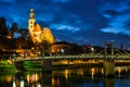 Leprosenhauskirche church and Mullner Steg bridge illuminated at night. Salzburg, Austria