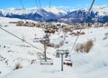 View from a ski chair lift moving up the mountain, in the Winter, above La Toussuire mountain village, part of Les Sybelles resort Royalty Free Stock Photo