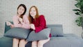 Lesbian Asian couple sing a song and dancing in living room at home, sweet couple enjoy funny moment while lying on the sofa when Royalty Free Stock Photo