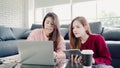 Lesbian Asian couple using laptop making budget in living room at home, sweet couple enjoy love moment while lying on the sofa Royalty Free Stock Photo