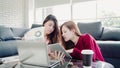 Lesbian Asian couple using laptop making budget in living room at home, sweet couple enjoy love moment while lying on the sofa Royalty Free Stock Photo