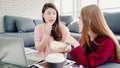 Lesbian Asian couple using laptop making budget in living room at home, sweet couple enjoy love moment while lying on the sofa Royalty Free Stock Photo