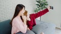 Lesbian Asian couple using smartphone selfie in living room at home, sweet couple enjoy funny moment while lying on the sofa when Royalty Free Stock Photo