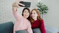 Lesbian Asian couple using smartphone selfie in living room at home, sweet couple enjoy funny moment while lying on the sofa when Royalty Free Stock Photo