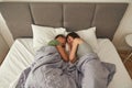 Lesbian couple with closed eyes laughing on bed