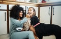 Lesbian, couple and happy with dog in kitchen, home or women eating breakfast together on the floor of apartment. Pet Royalty Free Stock Photo
