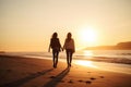 A lesbian couple holding hands walking along the beach at sunset. Royalty Free Stock Photo