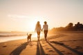 A lesbian couple holding hands walking along the beach with their dog at sunset. Royalty Free Stock Photo
