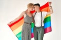 Lesbian couple of lovely women embracing and looking into each other`s eyes holding rainbow flag, symbol of the struggle for