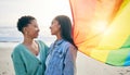 Lesbian couple, pride flag and freedom hug at beach for romance, happy or care in nature. Rainbow, love and women at the