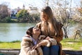 Lesbian couple sitting on a park bench. They look very much in love and happy as they are interacting with each other, talking,