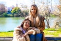 Lesbian couple sitting on a park bench. They look very much in love and happy as they are interacting with each other, talking,