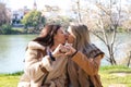 Lesbian couple sitting on a park bench. They look very much in love and happy while kissing and making a heart with their hands.