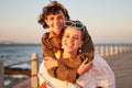 Lesbian, portrait and couple of friends at the beach in piggyback, support and happy for lgbtq love. Sunset, sea and Royalty Free Stock Photo