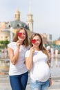 Lesbians mothers, pregnant couple, happy samesex family in the city park at summer. Women holding sweets, heart shaped Royalty Free Stock Photo