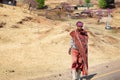 Lesotho, young african shepherd man in national red wool blanket dress and balaclava on rural high mountain road in village