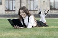 Lesson on fresh air. Cute small child reading book outdoors. Schoolgirl school uniform laying on lawn with favorite book