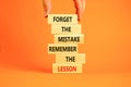 Lesson from mistake symbol. Concept words Forget the mistake remember the lesson on wooden blocks on a beautiful orange table