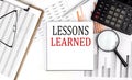 LESSONS LEARNED text on notebook with clipboard and calculator on a chart background Royalty Free Stock Photo