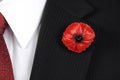 Lest We Forget Red Poppy Lapel Pin Badge on man's black suit.