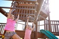 Let children be children for as long as possible. two little girls hanging on the monkey bars at the playground.