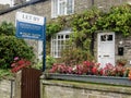 Let-by estate agent board in front of a traditional stone country cottage