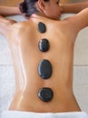 Let the heat release tension in your back and shoulders. a young woman enjoying a hot stone massage at a spa. Royalty Free Stock Photo