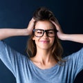 Let loose a little. Studio shot of a cute teenage girl in glasses with her hands in her hair posing against a dark Royalty Free Stock Photo