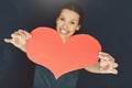 Let love lead. Portrait of a young woman posing with a heart against a gray background.