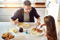 Let me have some...an adorable little girl having breakfast with her father in the kitchen. Royalty Free Stock Photo