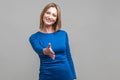 Let me introduce myself. Portrait of friendly woman giving hand to handshake, greeting guests with toothy smile. indoor studio Royalty Free Stock Photo