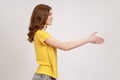 Let me introduce myself. Profile portrait of friendly brown haired teenager girl giving hand to handshake, greeting guests with Royalty Free Stock Photo