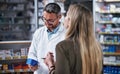 Let me just write the instructions on here. a mature pharmacist assisting a young woman in a chemist. Royalty Free Stock Photo