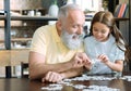 Grandfather and girl chatting while playing jigsaw puzzle