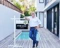 Let me show you around. Full length portrait of a handsome mature male real estate agent leaning on a for a sale sign. Royalty Free Stock Photo