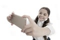 Let me take selfie. Girl cute long curly hair holds smartphone taking selfie white background. Child girl school uniform Royalty Free Stock Photo