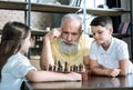 Thoughtful retired man playing chess with grandchildren Royalty Free Stock Photo