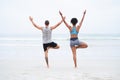 Let no storm overpower your soul. Rearview shot of a young man and woman practising yoga together at the beach.