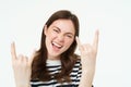 Let it rock. Excited, laughing young woman, showing heavy metal, horns gesture and smiling, having fun, expressing