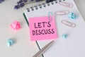 LET'S DISCUSS text on pink paper notebook on a chart with pen. Royalty Free Stock Photo