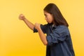 Let`s fight! Side view of confident courageous girl in denim shirt keeping fists clenched, boxing and punching to side