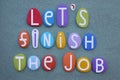 Let's finish the job, creative slogan composed with multi colored stone letters over green sand