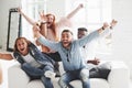 Let`s get a little bit crazy. Office friends have cheerful time sitting and laying on the white sofa Royalty Free Stock Photo