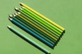 The concept of environmental protection: colored pencils in green shades on a green background top view.