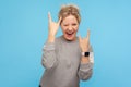 Let`s rock! Crazy funky woman with short curly hair in sweatshirt showing rock and roll gesture, devil horns hand sign Royalty Free Stock Photo