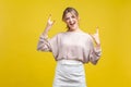 Let`s rock! Portrait of excited beautiful woman with blonde hair in casual beige blouse,  on yellow background Royalty Free Stock Photo